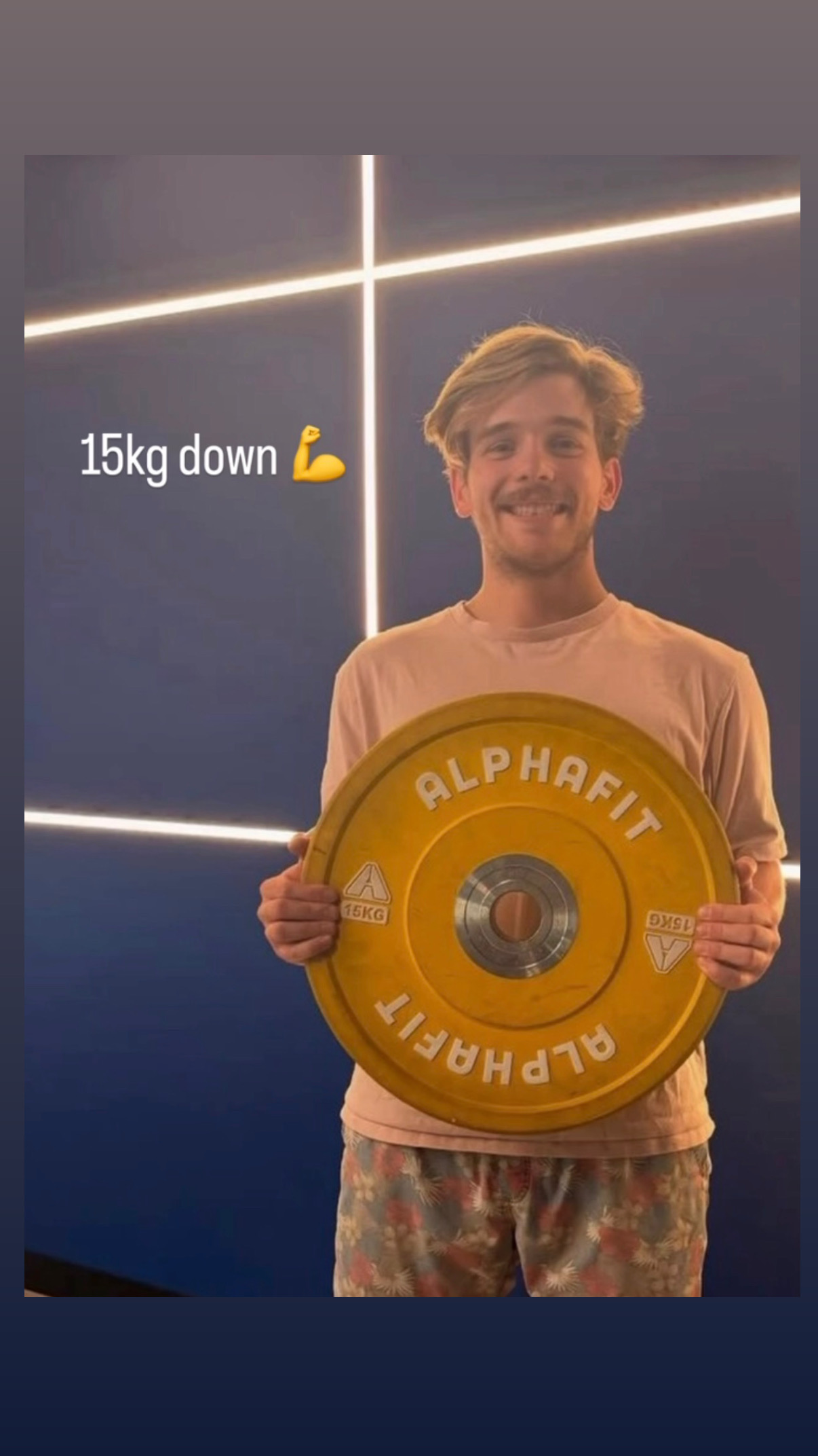 Thomas holding a 15 kilogram weight plate to mark his milestone